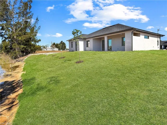 Spacious rear yard with a gentle slope leading to a natural water feature