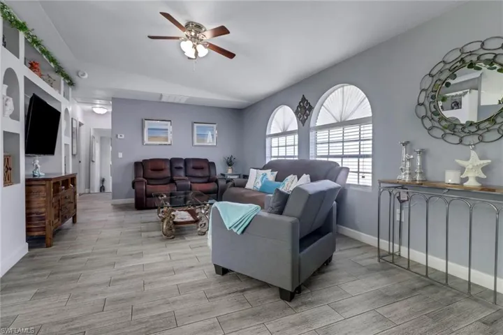 Living room featuring light wood-style floors, baseboards, visible vents, and ceiling fan