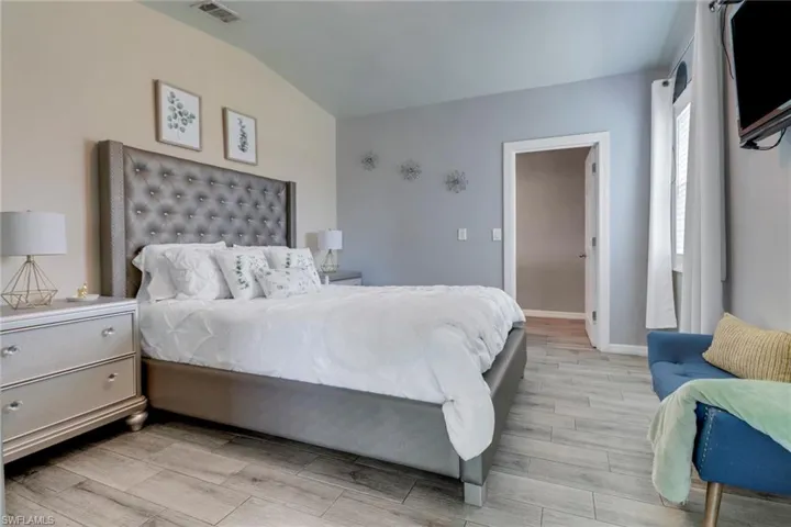 Bedroom with visible vents, baseboards, light wood finished floors, and lofted ceiling