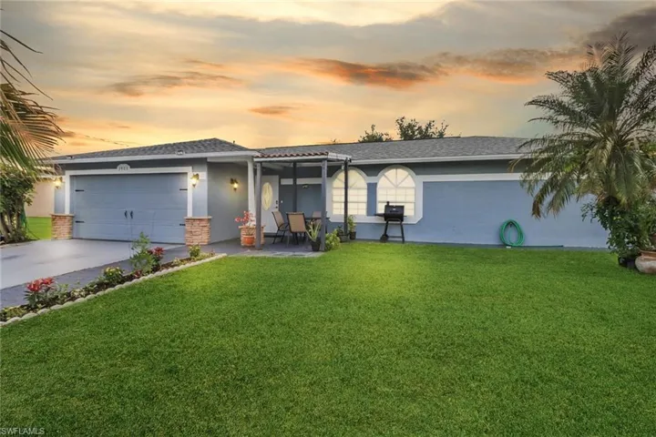 View of front of property featuring a front lawn, an attached garage, and stucco siding