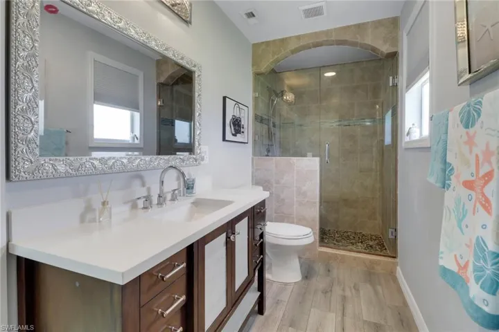 Full bathroom featuring toilet, visible vents, a stall shower, and a healthy amount of sunlight