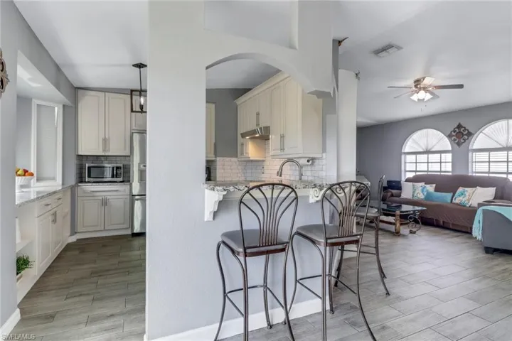 Kitchen with open floor plan, visible vents, a breakfast bar area, and appliances with stainless steel finishes
