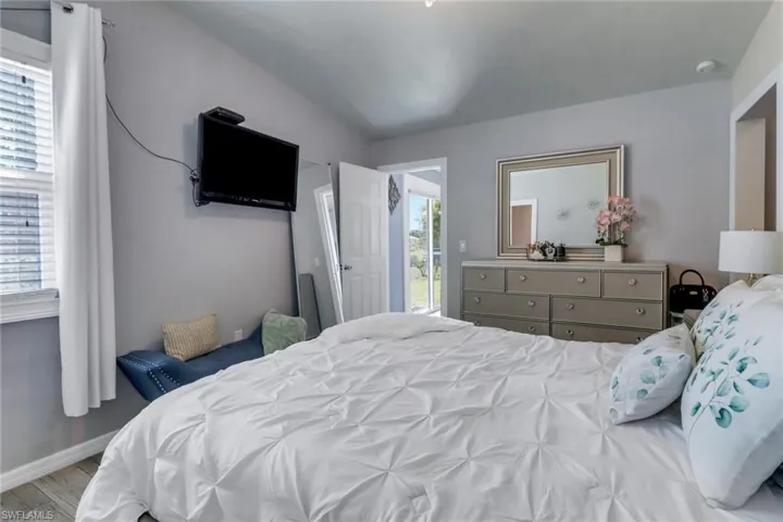 Bedroom featuring baseboards, multiple windows, and wood finished floors