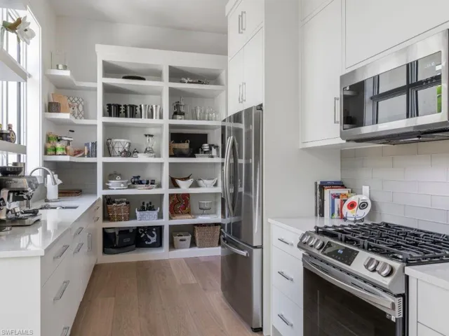 Catering Kitchen featuring tile backsplash, stainless steel appliances, and white cabinetry