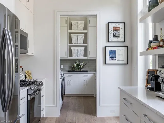 Catering Kitchen with white cabinets, stainless steel appliances, open shelves, and wood floors