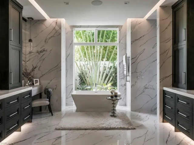 Primary Bathroom with floor to ceiling tiles, dual vanity, and a soaking tub