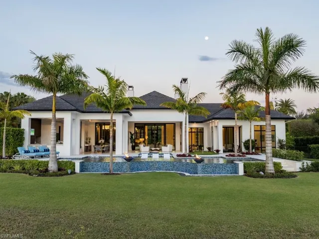 Back of property at dusk featuring an infinity edge pool