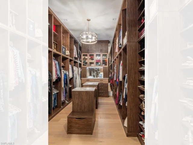 Primary walk in closet 1 with a chandelier and light wood-style flooring