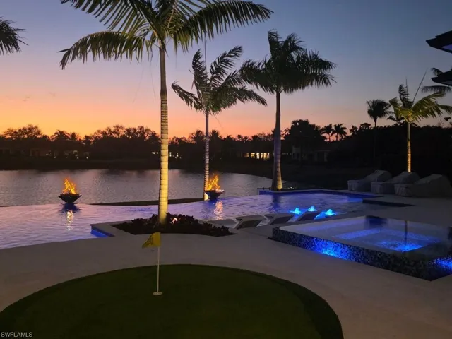 Pool at dusk with a putting green and a pool with connected hot tub