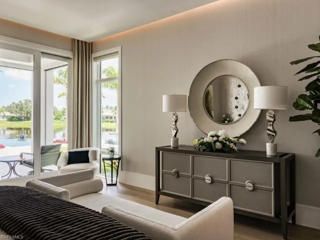 Primary Bedroom featuring sitting area with access to pool deck and putting green with views of the water