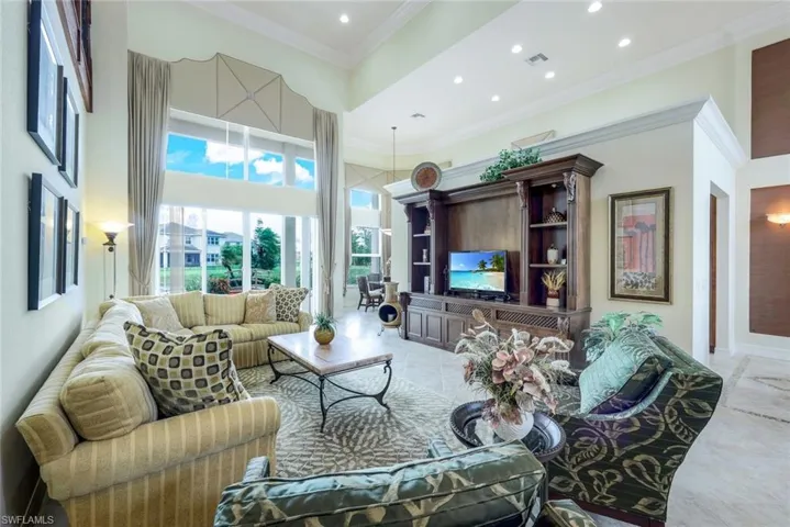 Living room featuring a towering ceiling, tile floors, and crown molding