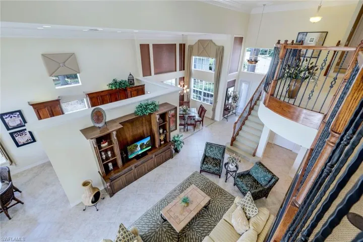 Tiled living room featuring a high ceiling and crown molding