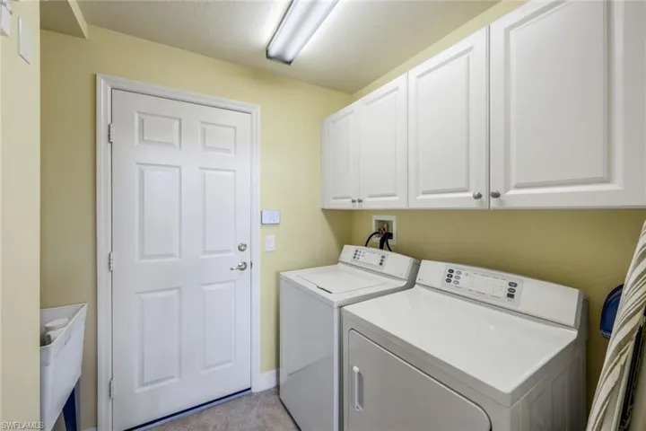 Washroom with washing machine and clothes dryer, washer hookup, cabinets, and light tile floors