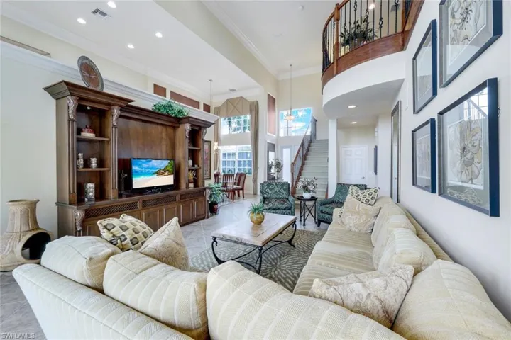 Living room featuring a towering ceiling, crown molding, and light tile floors