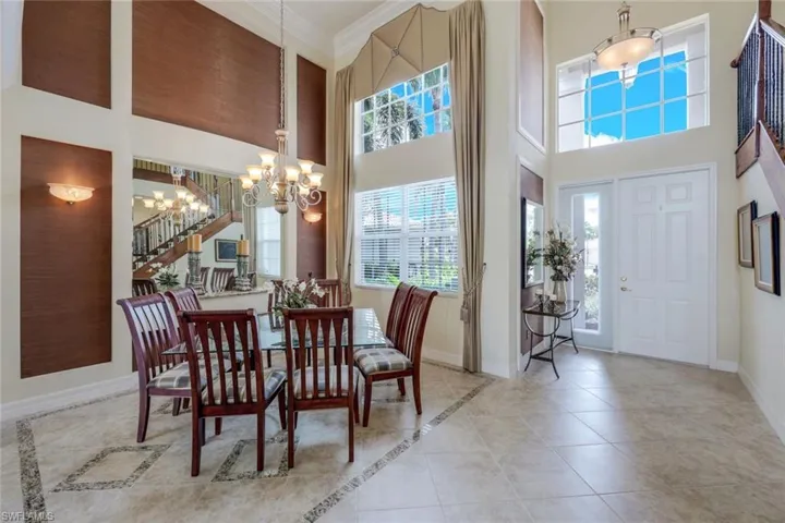 Tiled dining area featuring a high ceiling, crown molding, and an inviting chandelier