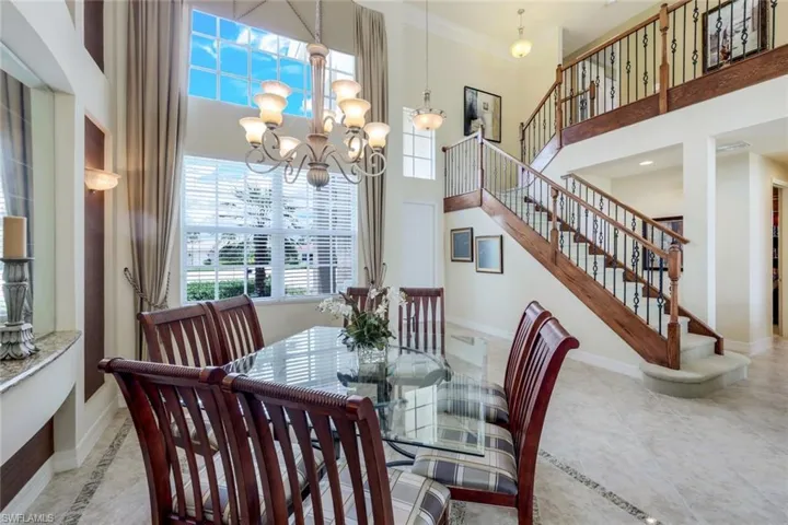 Dining room featuring tile floors, crown molding, a high ceiling, and an inviting chandelier