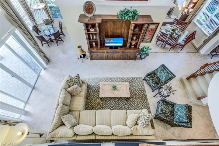 Tiled living room featuring a wealth of natural light, a towering ceiling, ornamental molding, and a chandelier