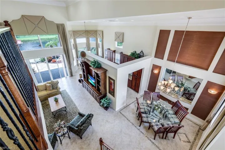Living room with a high ceiling, tile flooring, crown molding, and a chandelier