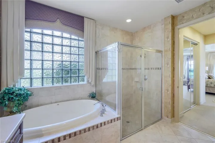 Bathroom featuring tile floors, a healthy amount of sunlight, separate shower and tub, and vanity