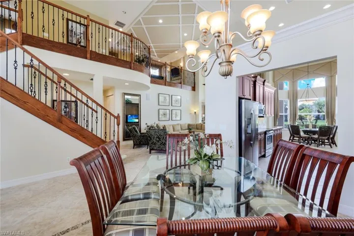 Dining area featuring a high ceiling, a notable chandelier, tile flooring, and crown molding