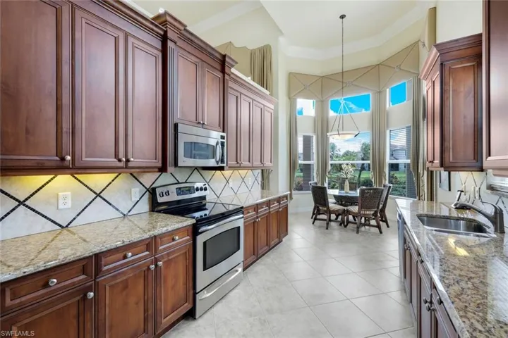 Kitchen featuring light tile flooring, hanging light fixtures, tasteful backsplash, appliances with stainless steel finishes, and sink