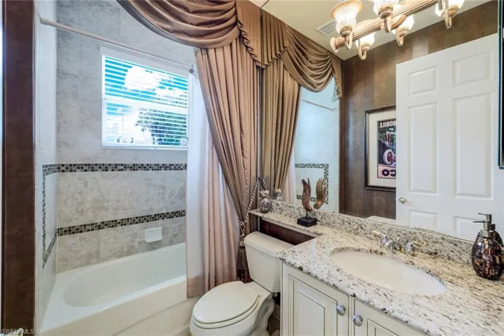 Full bathroom featuring a notable chandelier, toilet, shower / bath combo, and vanity