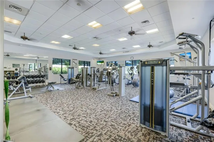 Exercise room with carpet, a paneled ceiling, and ceiling fan