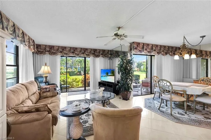 Living room featuring plenty of natural light, ceiling fan, a textured ceiling, light tile patterned flooring, and a chandelier