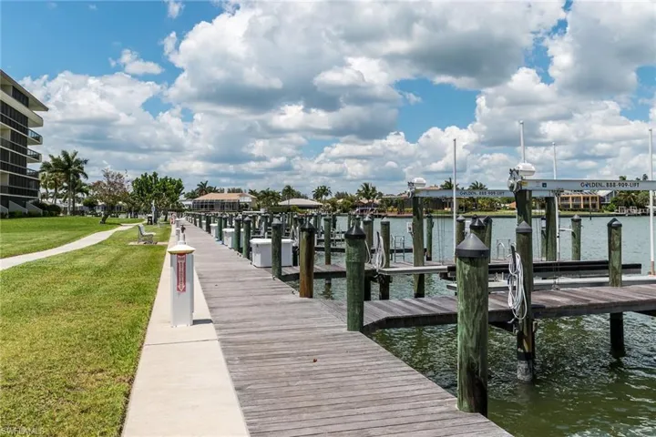 Dock with boat lift, a water view, and a yard