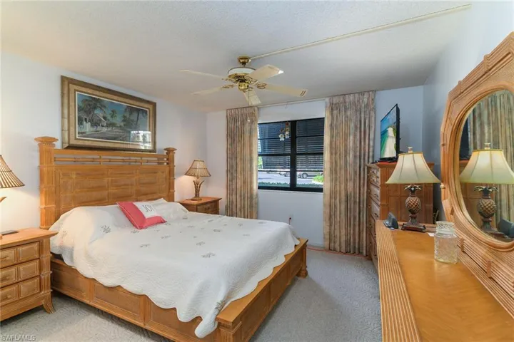 Bedroom featuring ceiling fan, a textured ceiling, and light carpet