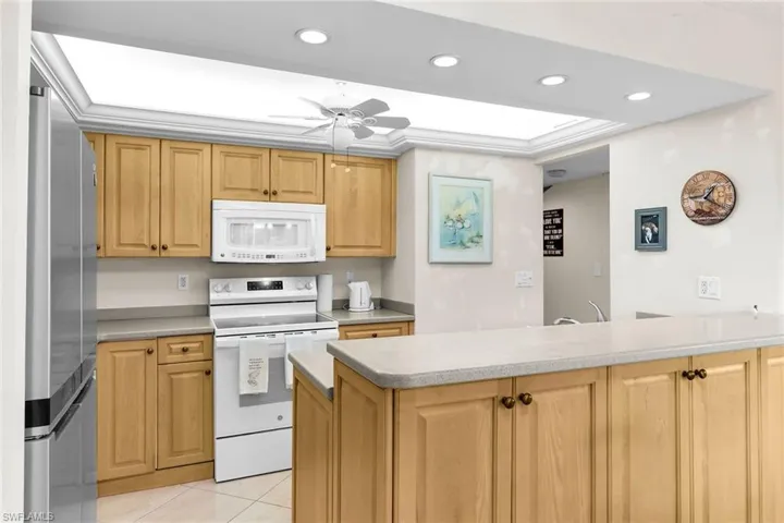 Kitchen featuring white appliances, recessed lighting, light brown cabinets, a peninsula, and a ceiling fan