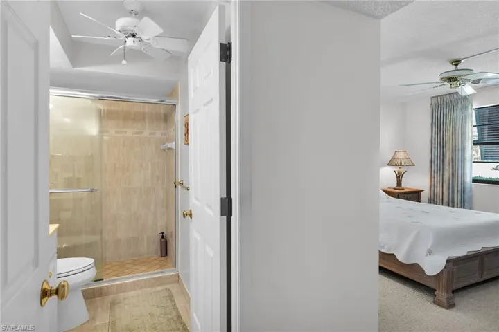 Bathroom featuring ceiling fan, ensuite bath, a shower stall, and a textured ceiling