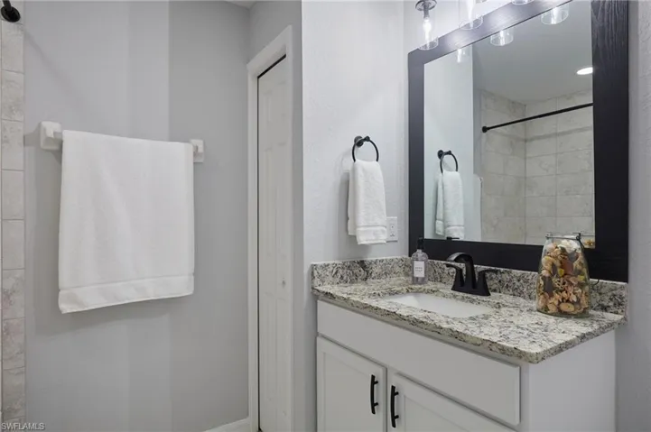Full bath featuring vanity, tiled shower, and a closet