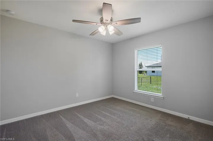 Empty room with carpet, ceiling fan, and a smoke detector