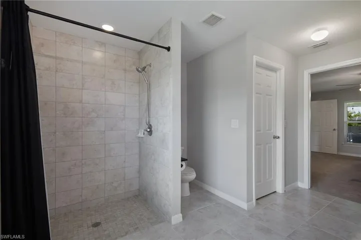 Full bathroom with a shower stall, ceiling fan, and light tile patterned floors