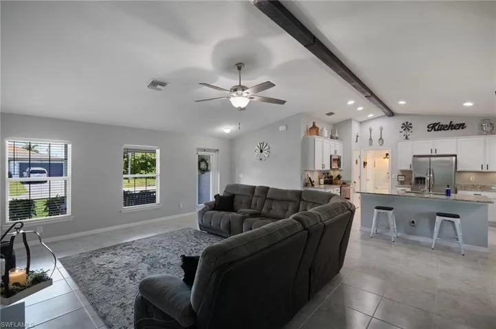 Living room with beam ceiling, recessed lighting, a ceiling fan, light tile patterned floors, and high vaulted ceiling