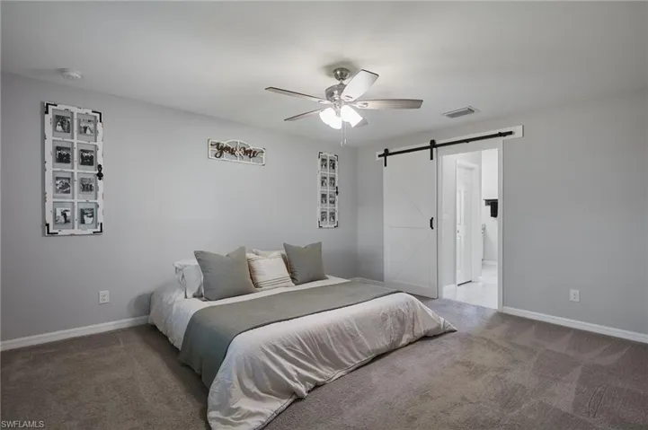 Bedroom featuring carpet floors, a barn door, and a ceiling fan
