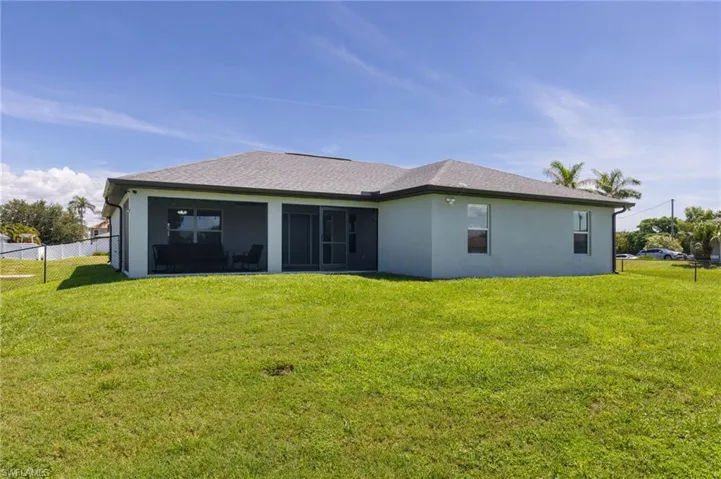 Rear view of house featuring stucco siding, a sunroom, and roof with shingles