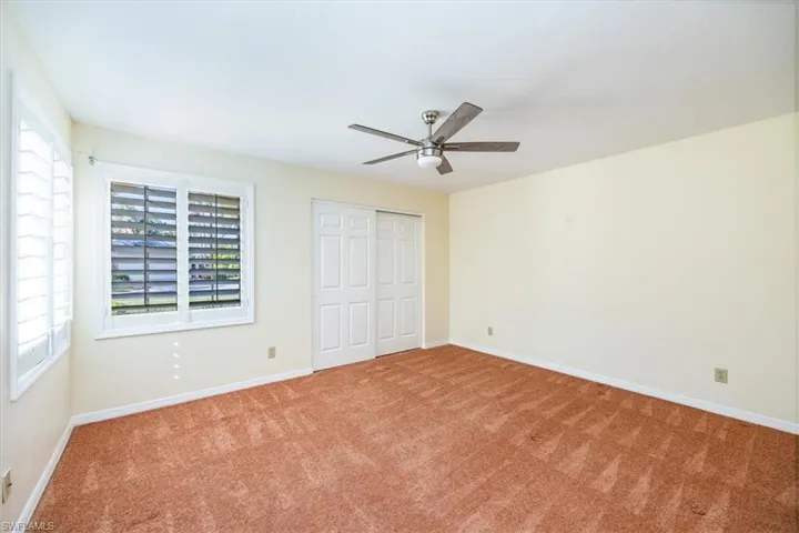 Unfurnished bedroom featuring ceiling fan and carpet floors
