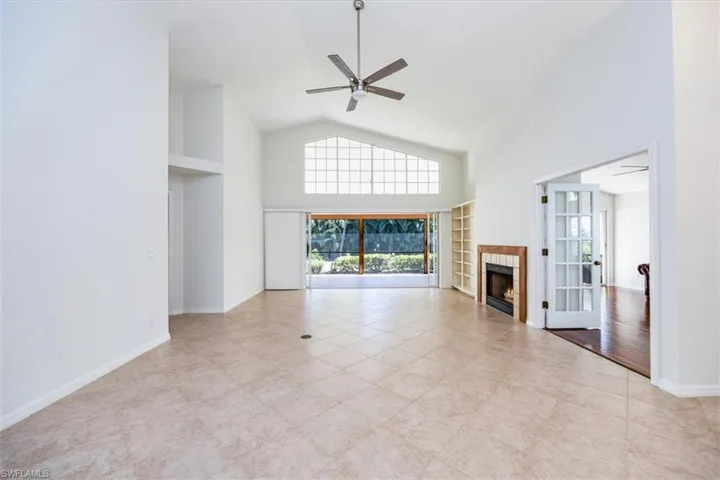 Unfurnished living room featuring a tile fireplace, ceiling fan, high vaulted ceiling, and light tile patterned flooring