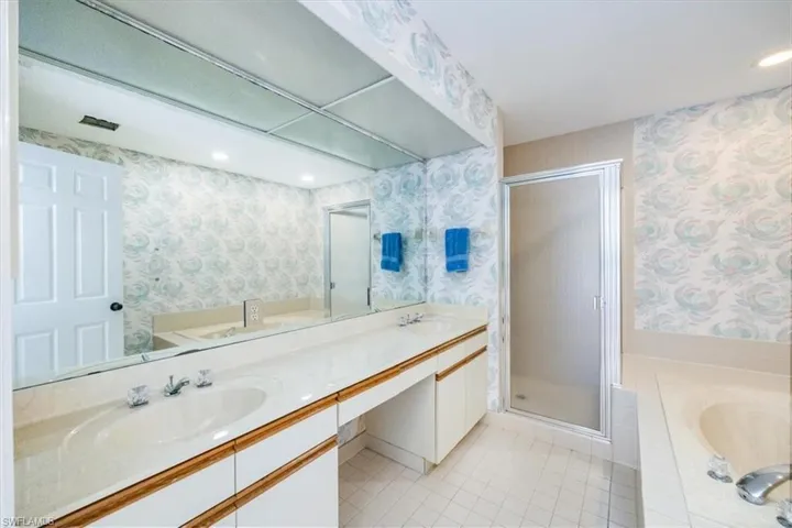 Bathroom featuring plus walk in shower, vanity, and tile patterned floors