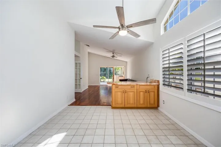 Kitchen featuring ceiling fan, sink, light tile patterned floors, and lofted ceiling