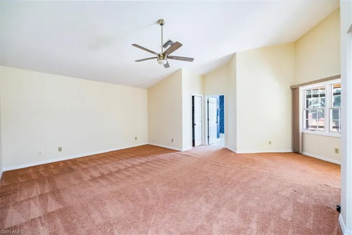 Unfurnished living room with light colored carpet, high vaulted ceiling, and ceiling fan