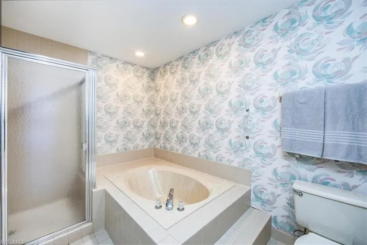 Bathroom featuring plus walk in shower, tile patterned flooring, and toilet