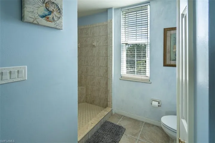 Full bathroom featuring a shower stall and light tile patterned flooring