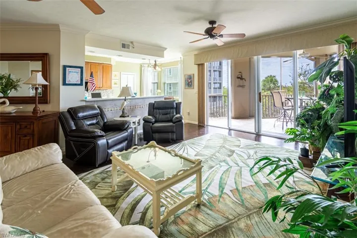Living area featuring a ceiling fan, crown molding, plenty of natural light, a chandelier, and wood finished floors