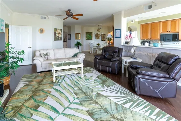 Living area with ornamental molding, a ceiling fan, and dark wood-type flooring