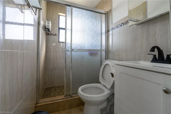 Full bathroom featuring vanity, a stall shower, and tile walls