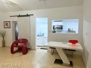 Dining room with a barn door and light tile patterned floors