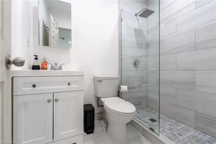 Full bath featuring vanity, tiled shower, and light tile patterned floors